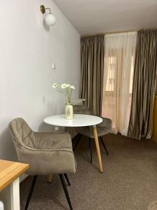 a room with a table and chairs and a vase with flowers at Montana Inn Slănic Moldova in Slănic-Moldova