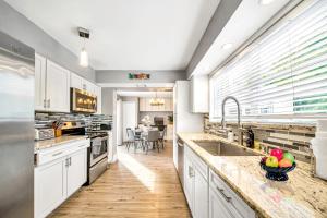 a large kitchen with white cabinets and a sink at Relax at Serenity Heated Pool Spa BBQ Near Beach in Palm Beach Gardens