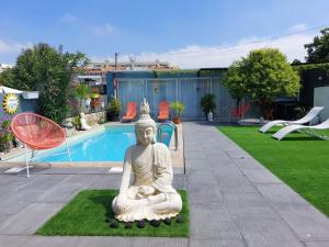 Eine Buddha-Statue, die auf dem Rasen neben einem Pool sitzt. in der Unterkunft Budha GuestHouse in Porto