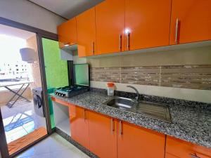 フェズにあるResidence Noor - Central Apartments Fesのキッチン(オレンジ色のキャビネット、シンク付)