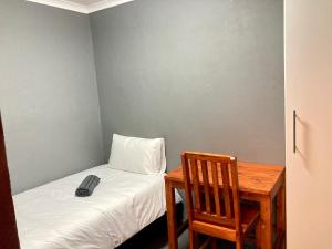 Unit 2 TraversHub Sleeps 6 Self-Catering Group Belhar, CT في Belhar: غرفة صغيرة مع سرير وطاولة مع ريموت كنترول