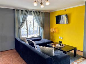Unit 2 TraversHub Sleeps 6 Self-Catering Group Belhar, CT في Belhar: غرفة معيشة مع أريكة زرقاء وطاولة