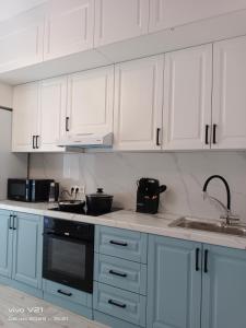 Una cocina blanca con gabinetes blancos y un fregadero. en Мадрид, en Astana 10 fotos más