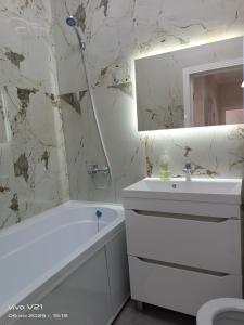 Un baño con bañera blanca, lavabo y espejo. en Мадрид, en Astana