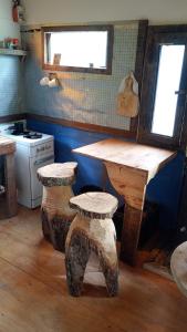 une cuisine avec une table et deux tabourets avec des bûches dans l'établissement Kailash, à La Porteña