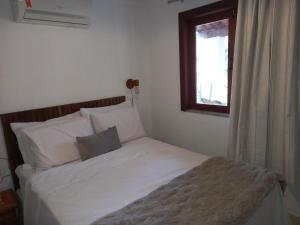 a bed with white sheets and a window in a room at Chalé Colibri in Vale do Capao
