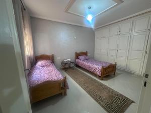 Dos camas en una habitación con armarios blancos. en appartement luxe, en Berkane