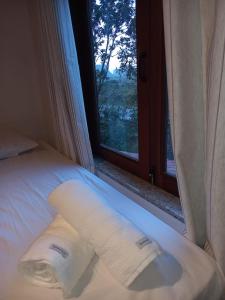 een bed met twee handdoeken naast een raam bij Chalé Colibri in Palmeiras