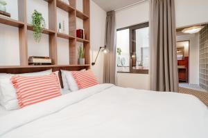 Dogpound Hotel في أثينا: غرفة نوم بسرير أبيض ومخدات حمراء وبيضاء +72 صورة