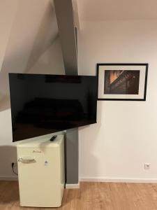 a flat screen tv on a wall next to a refrigerator at Luxus Ferien Apartment vS in Marburg an der Lahn