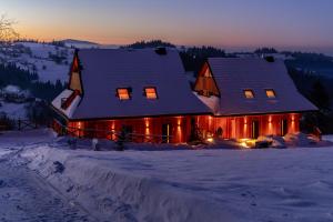 a house covered in snow with lights on it at Janiołów Wierch 43 Jacuzzi i Sauna in Groń