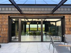 een glazen uitbreiding naar een huis met een patio bij Dom w czerni in Górniki