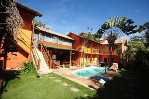a house with a swimming pool in front of it at Mandacaru Pousada in Porto Seguro