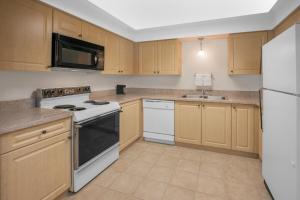 a kitchen with white appliances and wooden cabinets at Baymont by Wyndham Jackson in Jackson