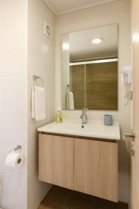 un baño con lavabo y espejo en la cuidad en las alturas, en Concepción