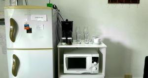 Departamento en El Calafate para dos personas في إل كالافاتي: ثلاجة بيضاء بجوار طاولة صغيرة مع ميكروويف