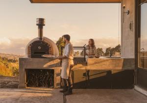 a man and woman standing in front of an outdoor oven at Summit Escape Peace & Comfort in Cartago +31 photos