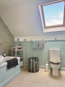 ein Bad mit einem WC, einer Badewanne und einem Fenster in der Unterkunft Charming Dog-Friendly Guesthouse in Sidbury