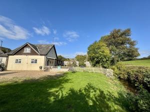 ein Haus mit einem Zaun vor einem Hof in der Unterkunft Charming Dog-Friendly Guesthouse in Sidbury