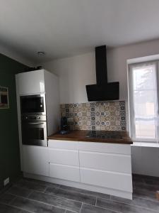 a kitchen with white cabinets and a stove at La Gilbertine in Louze +10 photos