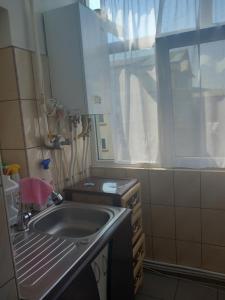 una piccola cucina con un lavandino e una finestra di Apartament a Curtea de Argeş
