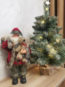 a santa claus holding two teddy bears next to a christmas tree at Holiday Baltic Sun in Sztutowo