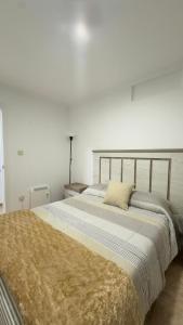 Cama grande en habitación blanca con colcha en La Casita de Toñita, en Valdoviño