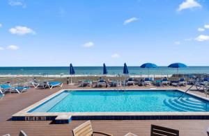 una piscina accanto alla spiaggia con sedie e ombrelloni di Serenity on Sable a Perdido Key Altre 18 foto