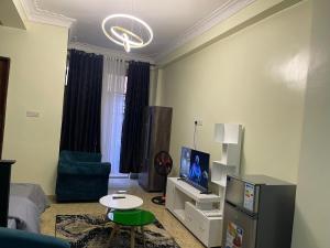 un salon avec un canapé, une télévision et une table dans l'établissement Hella home, à Kampala