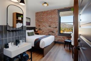 a bedroom with a bed and a sink and a brick wall at Lightwell Hotel & Spa in Hood River