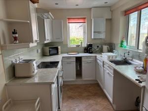a kitchen with white cabinets and a sink at Grayrigge Croft Cottage in Grange Over Sands