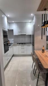 a kitchen with white cabinets and a wooden table at kriola Breeze in Praia