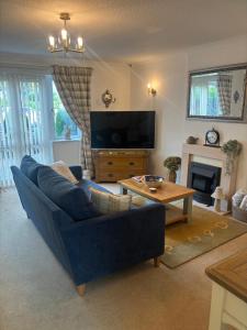 a living room with a blue couch and a tv at Grayrigge Croft Cottage in Grange Over Sands