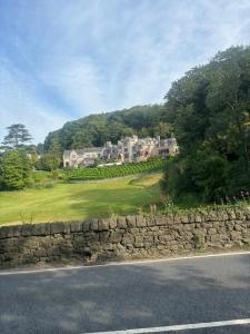 a house on a hill next to a stone wall at Grayrigge Croft Cottage in Grange Over Sands
