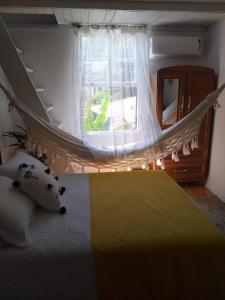 a bedroom with a bed with a yellow blanket and a window at Sambaqui - Casa de Hóspedes Kitinet in Florianópolis +29 photos