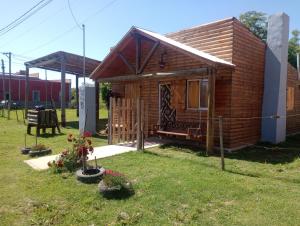 une petite cabane en bois dans une cour avec quelques fleurs dans l'établissement Cabaña el amanecer, à Dolores