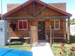 une cabane en rondins avec une porte et un banc dans l'établissement Cabaña el amanecer, à Dolores