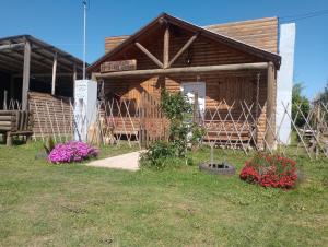 une cabane en rondins avec des fleurs devant dans l'établissement Cabaña el amanecer, à Dolores