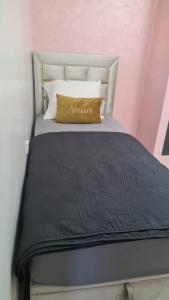 uma cama com um edredom preto e um travesseiro amarelo em Appartement Fes em Fez
