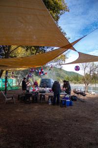 a group of people sitting at picnic tables under a tent at NaboCamp in Linares