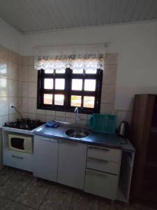 a small kitchen with a sink and a window at Apto com terraço coberto in Arroio do Sal