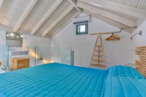 a bedroom with a blue bed and a ladder at Annika Deluxe Apartments in Symi