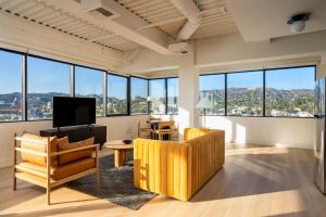 a living room with a couch and chairs and windows at Kasa Sunset Los Angeles in Los Angeles +2 photos