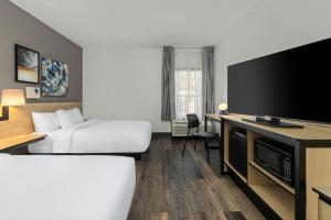a hotel room with two beds and a flat screen tv at City Express by Marriott Yulee in Yulee
