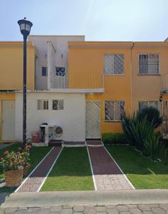 a yellow and white house with a yard at Casa en fraccionamiento en Ahuatepec con alberca, cancha y cerca de Tepoztlán 