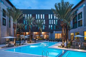 a pool with palm trees in front of a building at AC Hotel by Marriott Phoenix North Norterra in Phoenix