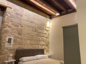 een slaapkamer met een stenen muur en een bed bij DaDa' Home in Trani