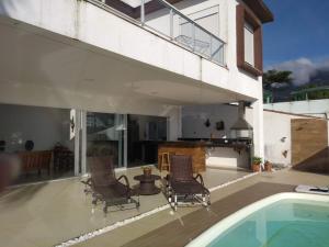 a patio with chairs and a swimming pool at Casa de Alto Padrão Piscina e Linda Vista para o Mar in Caraguatatuba