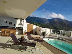 a patio with chairs and a swimming pool and mountains at Casa de Alto Padrão Piscina e Linda Vista para o Mar in Caraguatatuba