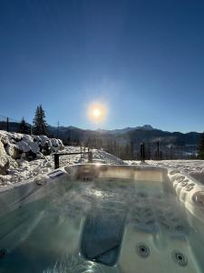 una vasca idromassaggio nella neve con il sole sullo sfondo di Stone Suite Zakopane a Zakopane